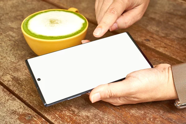 El masada bir cep telefonu ve yeşil çay bir bardak ile oynuyor         