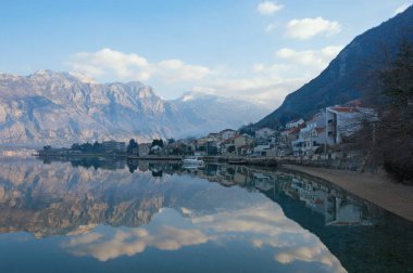 Güzel kış Akdeniz manzara - dağlar, beyaz bulutlar ve su yansıma ile mavi gökyüzü. Karadağ, Kotor Koyu'ndaki Adriyatik Denizi. Görünüm Stoliv Köyü