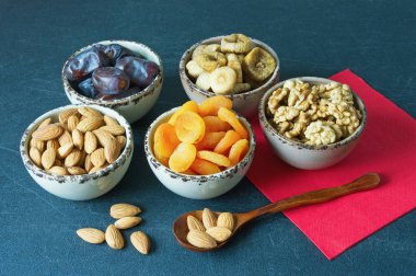 Çeşitli kurutulmuş meyve ve fındık koyu arka plan üzerinde küçük kase