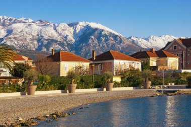Yeşil şehir karlı Dağları'nın eteklerinde. Ritimleri ile kırmızı çatılar ve beyaz dağ evleri. Karadağ, Kotor Koyu'nun güneşli kış gününde Tivat şehir ve Lovcen dağ set of görünümü