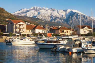 Güzel kış Akdeniz manzara. Balıkçı tekneleri Harbor karlı dağ zirveleri arka plan üzerinde. Karadağ, Kotor Körfezi. Marina Kalimanj Tivat şehir ve Lovcen Dağları'nın karla kaplı görünümünü