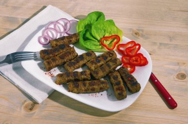 Balkan mutfağı. Cevapi - ızgara fincan kıyılmış et - beyaz tabakta sebze ile