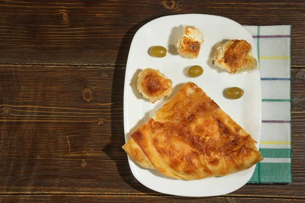 Cozinha balcânica. Burek com queijo, prato nacional popular. Deitado. Fundo rústico escuro. Espaço livre para texto — Fotografia de Stock