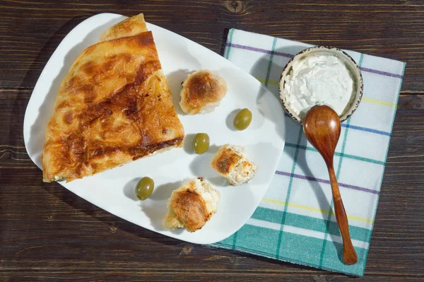 Cozinha balcânica. Burek com queijo é um prato nacional popular. Kajmak em prato pequeno. Deitado. Fundo rústico escuro — Fotografia de Stock