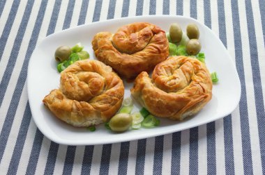 Balkan mutfağı. Burek, pişmiş dolgulu hamur işleri - popüler ulusal yemek. Beyaz bir tabak üzerinde üç yuvarlak bureks 