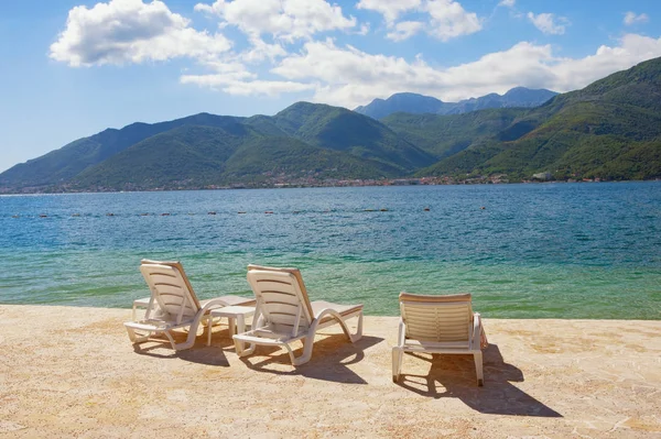 Sommarlovet. Vackert soligt landskap med schäslonger på stranden. Montenegro, Adriatiska havet, utsikt över bukten i Kotor nära Tivat stad — Stockfoto