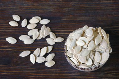 Koyu rustik arka plan üzerinde küçük bir kapta kurutulmuş kabak çekirdeği, düz yatıyordu