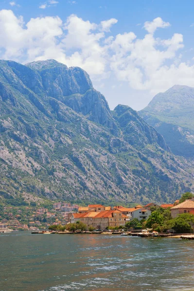 Picturesque Mediterranean landscape - mountains, sea and a small town with red roofs at the foot of the mountains. Montenegro, Kotor Bay (Adriatic Sea), Prcanj town