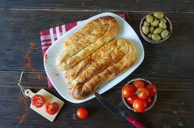 Balkan mutfağı. İki bureks - popüler ulusal yemek - beyaz plaka üzerinde. Düz yatıyordu. Koyu rustik arka plan