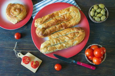 Balkan mutfağı. Bureks - popüler ulusal yemek - kırmızı tabaklarda. Düz yatıyordu. Koyu rustik arka plan