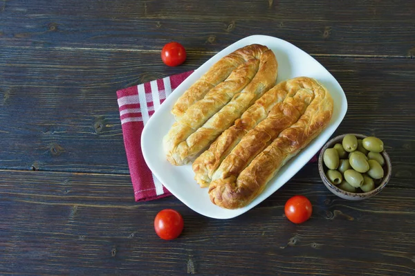 Cucina balcanica. Bureks - piatto nazionale popolare - su piatto bianco. Scuro sfondo rustico, spazio libero per il testo — Foto Stock