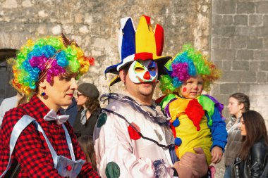 Kotor / Karadağ - Mart 03 2019: Geleneksel Kış Karnavalı. Eski Kotor Kasabası 'nın eski duvarlarına karşı Karnaval katılımcıları. Palyaçoların ailesi