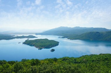 Yeşil dağların arasında küçük adaları olan mavi bir göl. Karadağ ve Niksiç 'in Salt Lake manzarası