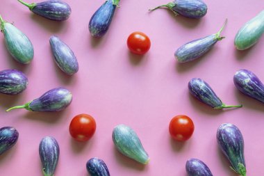 Pembe kağıt üzerinde mor patlıcan ve kırmızı domates. Boşluğu kopyala