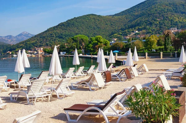 Plaj tatili Güneşli bir sonbahar gününde plaj şemsiyeli güzel Akdeniz manzarası. Karadağ, Adriyatik Denizi, Kotor Körfezi, Tivat