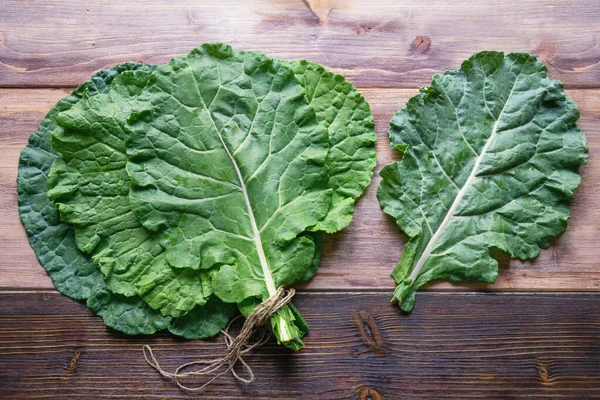 Leaves of rastan ( Collard greens, collards )  on rustic table. Flat lay, free space for text