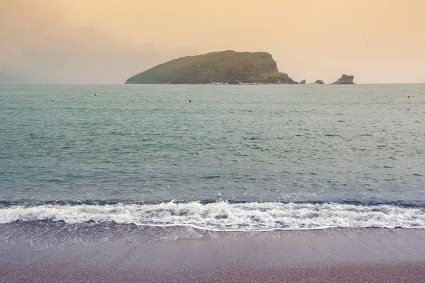 Bulutlu sonbahar günbatımı. Eski Budva Kasabası yakınlarında Adriyatik Denizi kıyısında. Sveti Nikola Adası manzarası. Karadağ