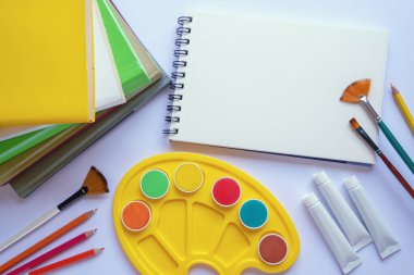 Kitap yığını, eskiz defteri, suluboya resimler, palet ve boya fırçaları. Düz yat, boşluğu kopyala