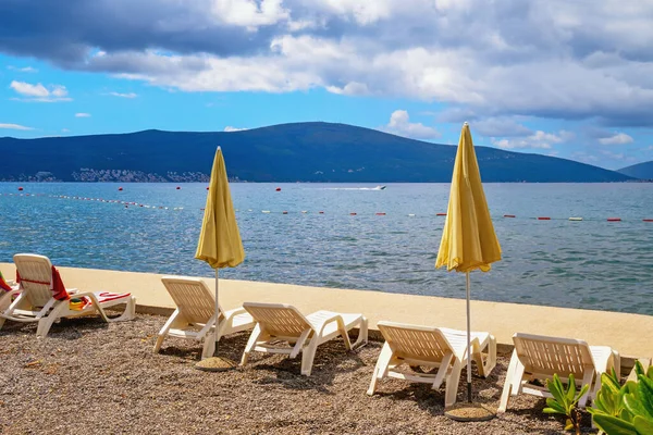 Sonbahar tatili. Karadağ, Tivat. Kotor Körfezi sahili manzaralı, şezlonglu ve plaj şemsiyeli.
