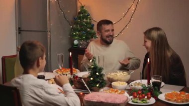 Mutlu bir aile yeni yıl arifesinde evde yemek yiyor. Noel ağacı, Noel ve yeni yıl konsepti