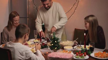 Mutlu bir aile ve iki arkadaş evde yemek yiyorlar.