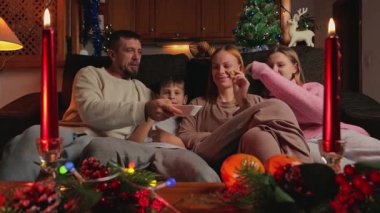 Genç ve mutlu bir aile Noel 'i evde kutluyor. Anne, baba ve kız şömineli sıcak bir akşam yemeği yiyorlar.