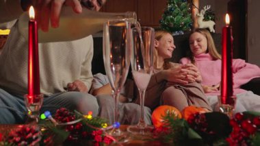 Mutlu bir aile Noel 'i evde kutluyor, kanepede oturuyor, şampanya tutuyor.