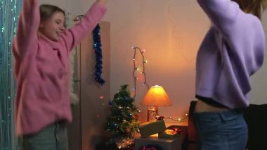İki kız dans ediyor ve Noel süslemeleriyle odada eğleniyorlar. Yeni yıl ve Noel tatili