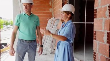 İnşaat alanında duran miğfer ve yelek giyen mühendis kadın mimar. Bir evde çalışan inşaat mühendisi.