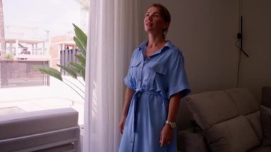 Pencerenin kenarında duran mavi elbiseli güzel genç kadın.