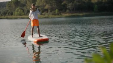 Genç adam yaz tatilinde gölde kürek çekiyor.