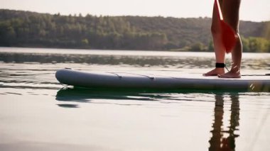 Bir insan kürek çekiyor, sakin sularda ustaca manevra yapıyor, doğal çevreyi yansıtıyor, macera duygusunu ve doğayla bağlantıyı somutlaştırıyor.