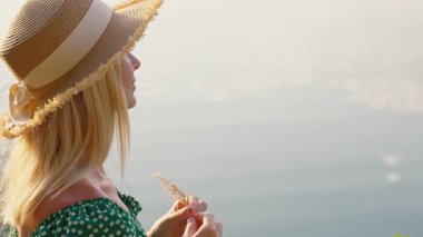 Gölde hasır şapka tutan genç bir kadın.