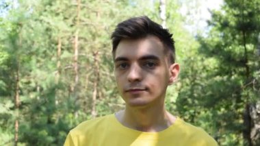 Doğa üzerine tişört giymiş dalgın bir gencin portresi.