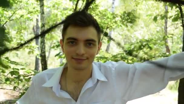 Ormandaki Genç Bir Adamın Portresindeki Yeşil Yaprakların Arasından Bak — Stok video