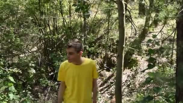 Un jeune homme en T-shirt marche dans les bois.
