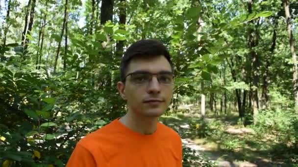 Portrét Mladého Muže Oranžovém Tričku Brýlemi Pozadí Zeleného Listí Lese — Stock video