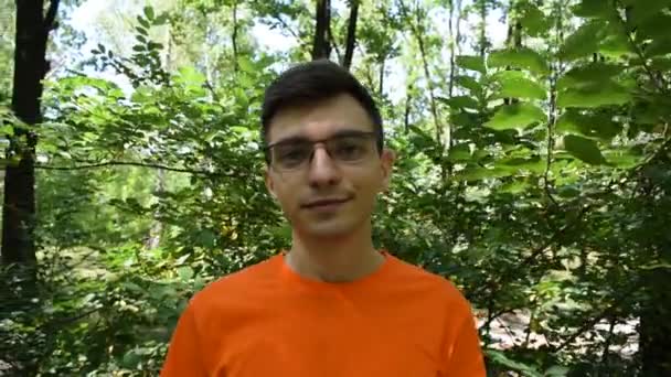 Retrato Jovem Uma Camiseta Laranja Com Óculos Fundo Folhagem Verde — Vídeo de Stock