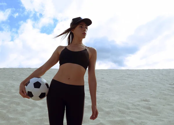 一个带着足球的胖胖的小女孩站在沙漠的沙滩上 — 图库照片