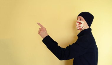 Siyah gömlekli, şapkalı, maskeli ve kanlı genç bir adam. Covid, ilaç.