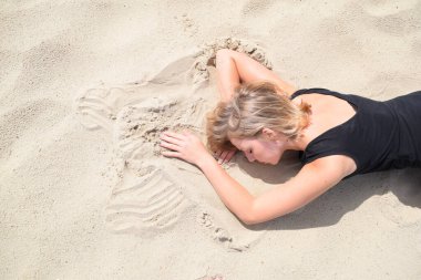 Çölde kumların üzerinde yatan genç bir kadın.