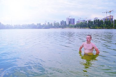 Genç adam şehrin yakınındaki gölde duruyor.