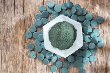 Spirulina toz ve tabletler ahşap arka plan üzerinde
