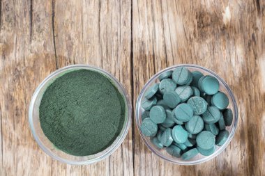 Spirulina toz ve tabletler ahşap arka plan üzerinde