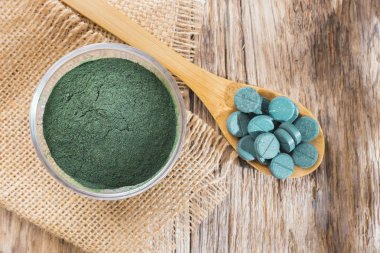 Spirulina toz ve tabletler ahşap arka plan üzerinde