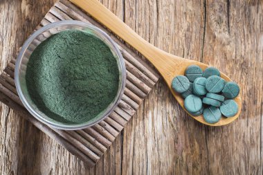 Spirulina toz ve tabletler ahşap arka plan üzerinde