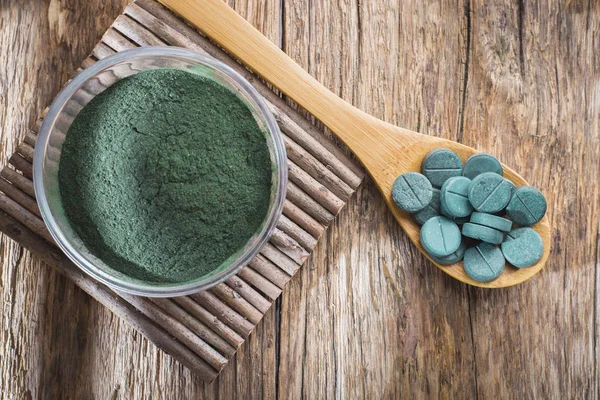 Spirulina toz ve tabletler ahşap arka plan üzerinde