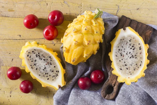 sarı pitahaya ya da ejderha meyve ve ahşap arka plan üzerinde kırmızı erik