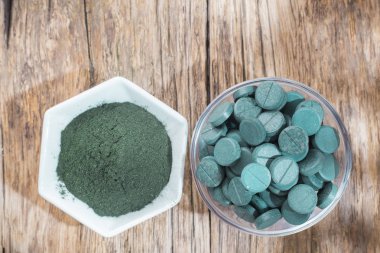 Spirulina toz ve tabletler ahşap arka plan üzerinde