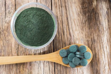 Spirulina toz ve tabletler ahşap arka plan üzerinde